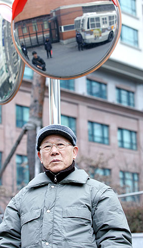대사관 맞은편에서 1인시위 중인 서상호 원로 머리 위 볼록거울로 일본대사관을 경비하고 있는 경찰들이 보인다. 대사관 측은 주한 일본대사관 입구 앞에서의 1인시위를 불허했다. [사진-통일뉴스 김주영 기자]