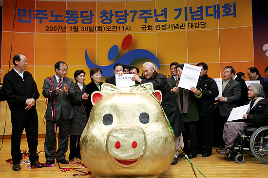 민주노동당 창당 7주년 기념식이 30일 오전 11시 서울 여의도 국회의사당 헌정기념관 대강당에서 당 지도부와 내외빈 300여명이 참석해 열린 가운데 진보진영 인사들를 비롯한 당 지도부들이 황금돼지에 '민노당 표'를 넣는 퍼포먼스를 하고 있다.  [사진-통일뉴스 김주영 기자]