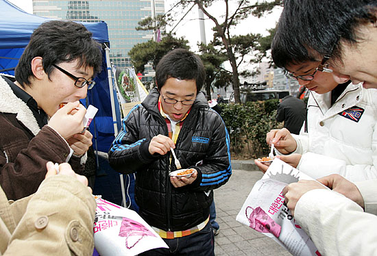 '고기 먹으랴, 선전물 보랴~ 바쁘다 바뻐!'시식용 불고기를 받아든 학생들이 시식과 선전물 읽기에 여념없다. [사진-통일뉴스 김주영 기자]