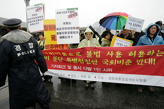 2일 국회 통일외교통상위원회(위원장 김원웅)가 전체회의를 열고 '7차 방위비 분담 특별협정'을 의결할 예정인 가운데 오전 10시 '평화와통일을여는사람들'(평통사) 소속 회원 10여명이 특별협정의 국회비준을 반대하며 정문 앞 기자회견을 시도하고 있다. 사진은 갑자기 등장한 평통사 회원들과 플랜카드를 보며 정황을 살피는 경찰의 모습.[사진-통일뉴스 김주영 기자]