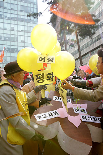 수요집회를 마친 할머니들과 참가자들이 '평화'와 '여성'이 새겨진 노란 풍선을 하늘로 날렸다. [사진-통일뉴스 김주영 기자]
