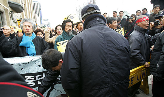 행진대열이 광화문 동아일보사 앞에서 경찰의 폴리스 라인에 가로 막힌 가운데 경찰측 관계자가 '횡단보도를 건너려면 플랜카드를 접고 가라'는 요구를 하고 있다.[사진-통일뉴스 김주영 기자]