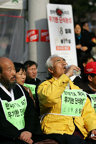 노숙단식농성 8일째를 맞은 오종렬 범국본 공동대표가 물을 마시고 있다(오른쪽). 봄 볕에 농성을 진행중인 대표자들의 얼굴이 검게 그을렸다. [사진-통일뉴스 김주영 기자]