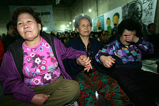 24일 오후 4시 20분경 이달 말 이주를 앞둔 대추리주민들이 마지막 촛불집회에 앞서 마을 곳곳에 새겨진 벽시들을 모은 시집 '마을이 거기 있었다'출판기념회를 진행한 가운데 주민들이 시 낭송을 들으며 손을 맞잡고 있다.  [사진-통일뉴스 김주영 기자]