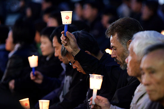 16일 오후 7시 고인이 숨을 거둔 한강성심병원 앞에서 열린 추모제 참석자가 촛불을 든 채 생각에 잠겨있다. [사진-통일뉴스 김주영 기자]