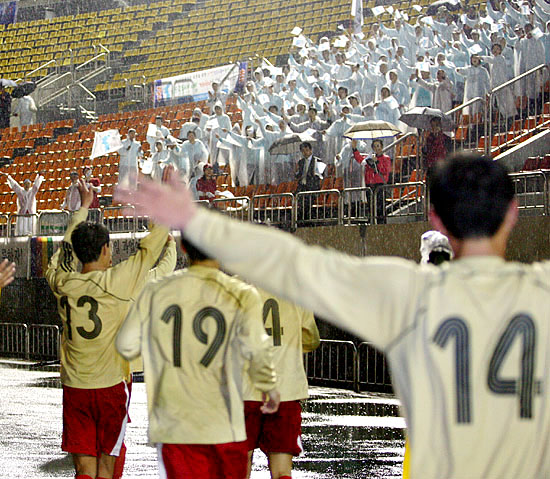 굵은 빗발이 들이치는 가운데 열린 남북노동자통일축구 대항전 경기가 끝나고 남북 선수들이 마지막까지 남아있는 관중들에게 인사를 하며 경기장을 나갔다. [사진-통일뉴스 김주영 기자]