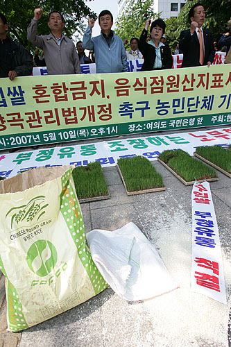 최근 국내산 쌀과 혼합된 수입쌀이 국내산으로 둔갑 유통되는 것을 적발한 농민단체가 10일 오후 1시 국회의사당 앞에서 기자회견을 열고 수입쌀 혼합을 금지하도록 양곡관리법 개정을 요구하고 나섰다. 가운데 흰 쌀포대가 혼합쌀이 담겨있던 포대.[사진-통일뉴스 김주영 기자]