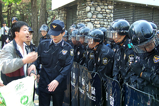 경찰에 가로막힌 성난 농민이 수입쌀을 집어던지며 길을 열 것을 요구하고 있다. [사진-통일뉴스 박현범 기자]