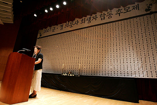 의문사한 손상규 장병의 어머니가 아들에게 보내는 '하늘로 부치는 편지'를 낭독하고 있다. 뒤로는 의문사 진정 접수된 600명의 군 장병 영령들의 이름이 보인다. [사진-통일뉴스 김주영 기자]