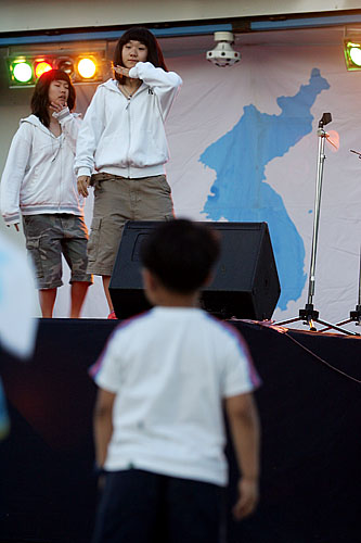 '눈을 뗄 수 없는 이유?'. 행사장 인근을 뛰다니며 놀던 아이는 경인중학교 여학생들의 축하 공연에 눈을 떼지 못하고 있다.[사진-통일뉴스 김주영 기자]
