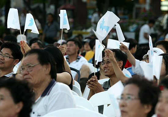 이웃들의 통일노래에 단일기를 흔들며 환화하는 주민들. [사진-통일뉴스 김주영 기자]