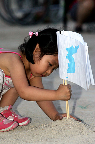 어린이들은 얼마 안되는 모래 한 줌에 단일기를 꽂기에 여념없다. [사진-통일뉴스 김주영 기자]
