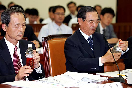 25일 오전10시 국회 환경노동위원회에 출석한 김장수 국방부 장관(왼쪽)과 윤광웅 전 국방부장관(오른쪽)이 열린우리당 제종길 의원이 제출한 반환미군기지 추출 오염토양과 기름 냄새를 맡아보고 있다.[사진-통일뉴스 김주영 기자]