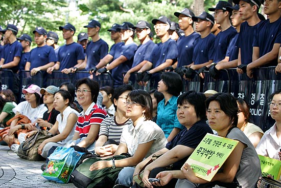 열린시민공원을 둘러싼 경찰병력의 진입에 대비, 천막을 설치하는 동안 농성참가자들이 연좌하고 있다. [사진-통일뉴스 김주영 기자]