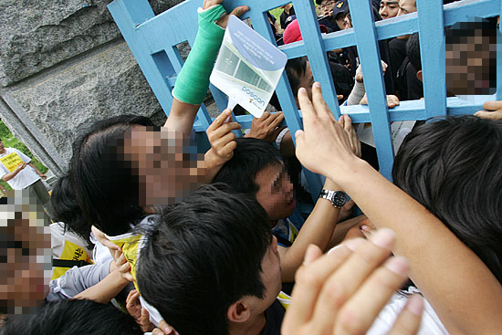 '아수라장 된 서울구치소 정문'. 경찰의 진압으로 정문 밖으로 밀려나는 과정에서 미처 빠져나오지 못한 실천단 참가자들이 문 사이에 끼어 고통을 호소하고 있다. [사진-통일뉴스 김주영 기자]