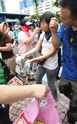 '물폭탄 맞은 조합원들'. 매장건물 위에서 갑자기 날아든 물폭탄에 맞아 옷이 젖은 이랜드 노조원들이 물이 들어있던 봉지를 확인하며 당황해 하고 있다. [사진-통일뉴스 김주영 기자]