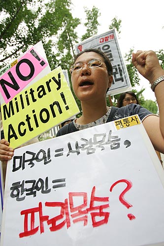 '평화와통일을여는사람들' 미군문제팀 이경아 부장이 미국의 군사작전을 반대하는 피켓을 들고 있다. [사진-통일뉴스 김주영 기자]