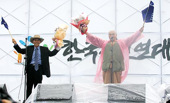 꽃다발을 받아든 정광훈, 오종렬 상임공동위원장이 참가자들의 환영박수에 화답하고 있다. [사진-통일뉴스 김주영 기자]
