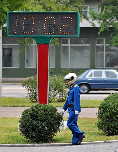 평양시내의 전자 시계판 앞을 지나는 교통경찰. [사진-청와대 사진기자단]