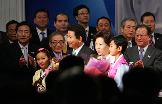 화동에게 꽃을 건네받은 노무현 대통령이 밝은 표정으로 수행원들과 함께 환영객들에게 인사를 전하고 있다. [사진-통일뉴스 김주영 기자]