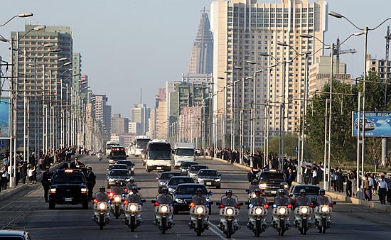 평양 시내를 달리는 노무현 대통령 일행을 보기 위해 나온 평양 시민들이 도로 위로 줄지어 있다. 도로 양 옆에는 높은 건물들이 눈에 띈다. [사진-청와대 사진기자단]