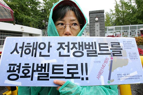 평택범대위 오두희 공동집행위원장이 군산 미공군기지와 제주도 해군.공군기지(2014년까지 건설계획) 등으로 둘러싸일 서해지역을 평화지대로 바꿀 것을 촉구하는 피켓을 들고 있다. [사진-통일뉴스 김주영 기자]