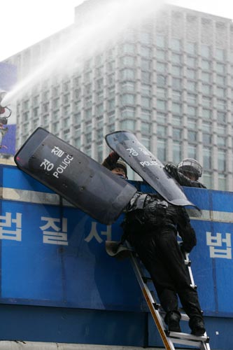 경찰 바리케이트를 사다리로 넘는 참가자들을 향해 방패를 마구잡이로 휘두르는 경찰. [사진-통일뉴스 김주영 기자]