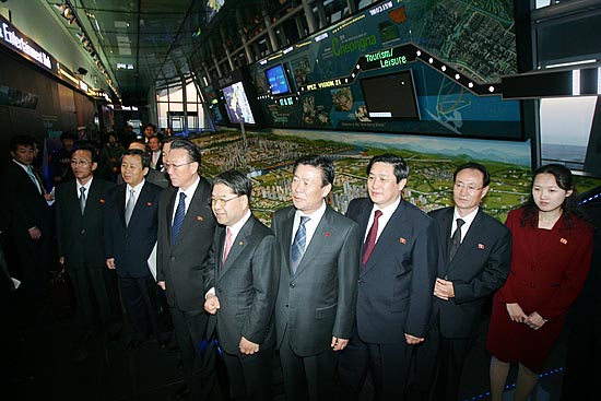 홍보용 로봇 '장금이'를 향해 기념촬영 포즈를 취하는 김양건 통전부장 일행. [사진-통일뉴스 김주영 기자]