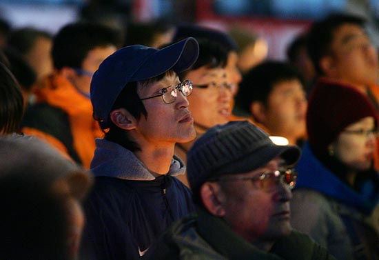 '이명박 동영상'이 공개 된 다음날인 17일 오후 7시 서울 광화문 동화면세점 앞에서 이명박 후보의 사퇴를 촉구하는 촛불문화제가 열렸다. '이명박 동영상'을 지켜보는 시민들. [사진-통일뉴스 김주영 기자]