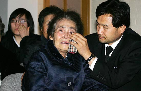 선생의 생전활동 모습을 영상으로 지켜보다 오열하는 부인 장영심 여사. 고인의 양자나 다름없는 김종대 씨가 눈물을 닦아주며 위로하고 있다. [사진-통일뉴스 김주영 기자]