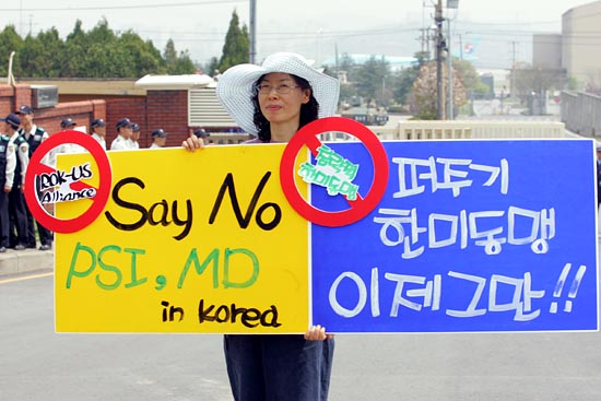 피켓시위를 하는 시민사회단체회원 뒷편으로 이명박 대통령이 탄 전용기가 보인다.[사진-통일뉴스 조성봉 기자