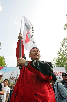 민주노총 깃발을 높이 올리며 투쟁의 결의를 밝히는 이석행 위원장.[사진-통일뉴스 조성봉 기자]
