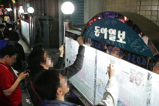 촛불문화제 참가자들이 <동아일보> 보도를 비판하는 글을 립스틱과 양초로 쓰고 있다.[사진-통일뉴스 조성봉 기자]