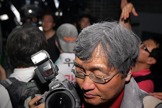 정면에서 분말소화기를 맞아 눈을 감고 있는 사진기자.[사진-통일뉴스 조성봉 기자]