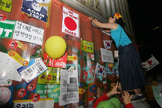 대형컨테이너에 한 시민이 '협상무효, 고시철회'구호가 적힌 손피켓을 달고 있다.[사진-통일뉴스 조성봉 기자]