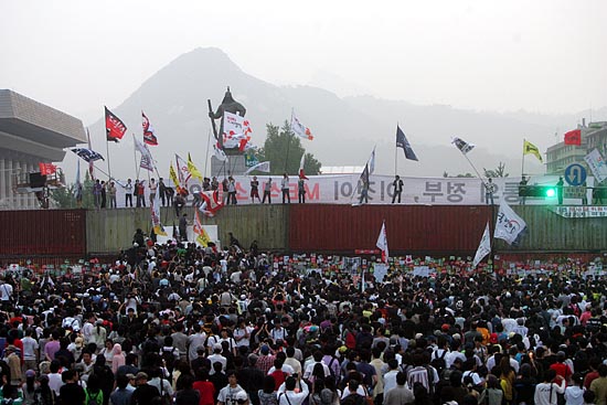 11일 새벽 4시 50분 대형컨테이너 위로 올라간 시민들이 '이명박 정부, 이것이 MB식 소통인가'라고 현수막을 청와대 방향으로 내걸고 깃발을 흔들고 있다. [사진-통일뉴스 조성봉 기자]