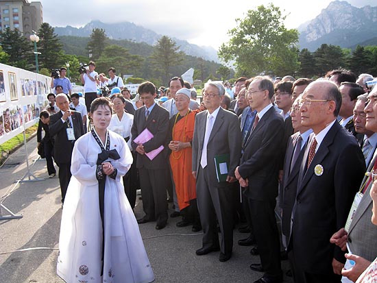 온정각 앞마당에서 열린 사진전 개막식에서 북측 해설원이 사진들을 설명하고 있다. [사진제공-6.15남측위]