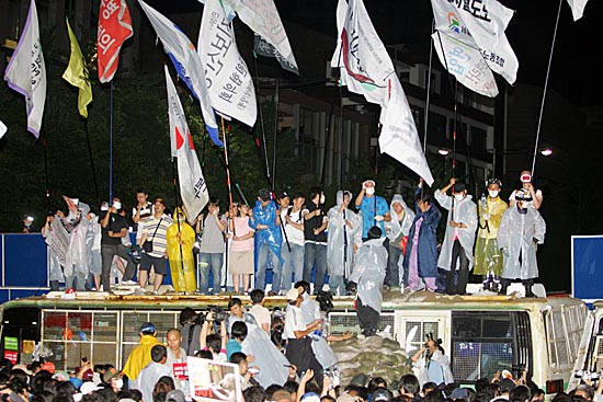 시민들이 '국민토성'을 통해 경찰버스 위로 올라 깃발을 흔들고 있다. [사진-통일뉴스 조성봉 기자]