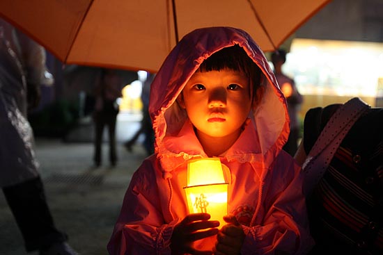 비가 오고 있는 가운데 촛불을 들고 있는 어린아이.[사진-통일뉴스 조성봉 기자]