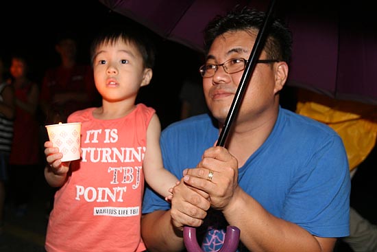 아빠와 함께 우산을 쓰며 촛불을 밝히고 있는 어린이.[사진-통일뉴스 조성봉 기자]