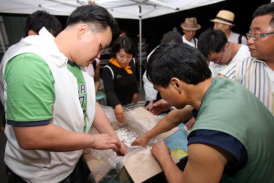'무건리 훈련장 확장 반대'를 위한 촛불문화제 첫 시작을 기념하는 떡을 참가자들에게 나눠주고 있다.[사진-통일뉴스 조성봉 기자]