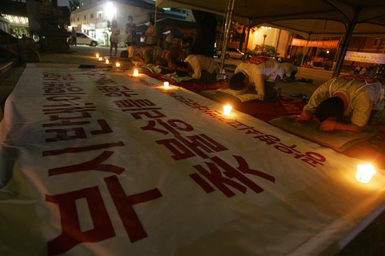 어둠 속에서 절을 하고 있는 '촛불 수배자'들 앞에는 촛불이 환하게 피어오르고 있다.[사진-통일뉴스 조성봉 기자]