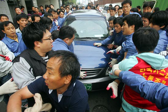 용역직원들과 회사 직원들이 차를 에워싸고 있다. [사진-통일뉴스 조성봉 기자]