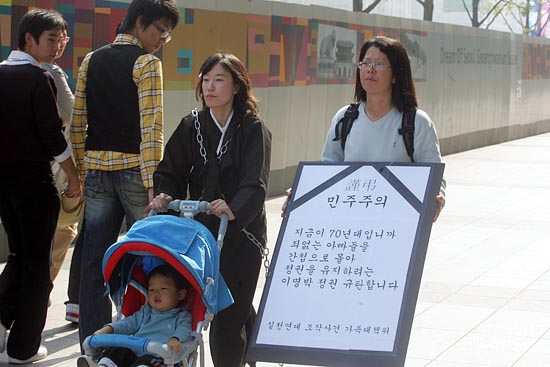 18일 낮 12시 국가보안보안법으로 구속된 '남북공동선언실천연대' 최한욱 집행위원장의 부인 하유진씨(왼쪽)가 상복 차림에 쇠사슬을 온몸에 두르고 아이와 함께 보신각에서 청와대까지 행진했다. [사진-통일뉴스 조성봉 기자]