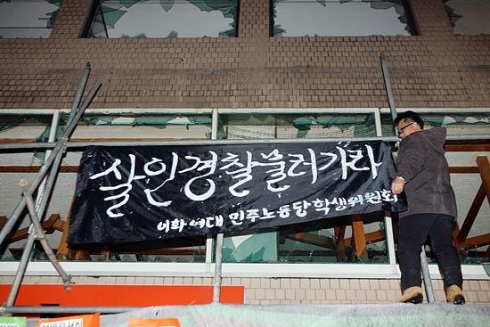 '살인 경찰 물러가라'플랭카드를 사건현장 건물에 걸어 놓는 한 참가자.[ 사진-통일뉴스 조성봉 기자]