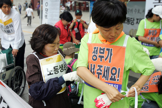 곽정숙 민주노동당 의원이 쌍용자동차 가족들의 삼보일배 준비를 도와주고 있다.[사진-통일뉴스 조성봉 기자]