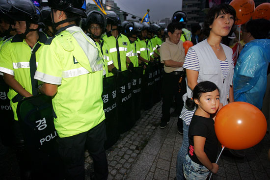 경찰이 인간띠잇기 행사에 참가한 시민들을 에워싸려고 하자 한 아이가 엄마의 손을 꼭 잡고 있다. [사진-통일뉴스 조성봉 기자]