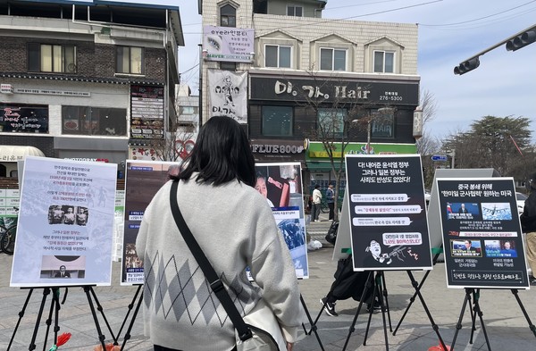지나가던 대학생이 피해자들의 증언과 사진을 유심히 보고 있다. [사진-통일뉴스 이민재 통신원]