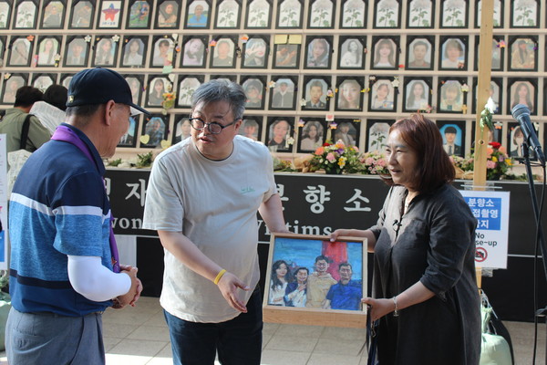 박향미 작가가 유가족에게 작품을 전달하고 있다. 가운데 신범식 창작단장. [사진-통일뉴스 이승현 기자]