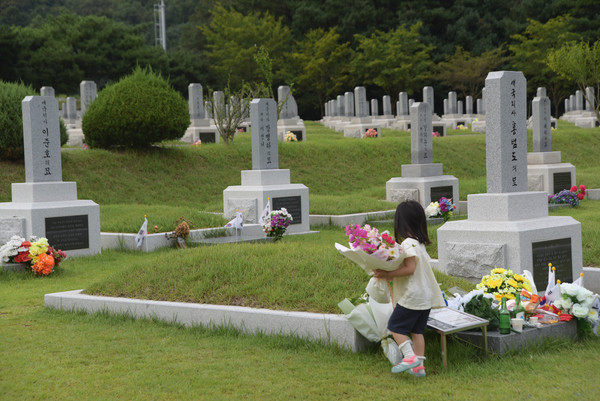 아이가 꽃다발을 홍범도 장군 묘 앞에 놓고 있다. [사진-통일뉴스 임재근 객원기자]